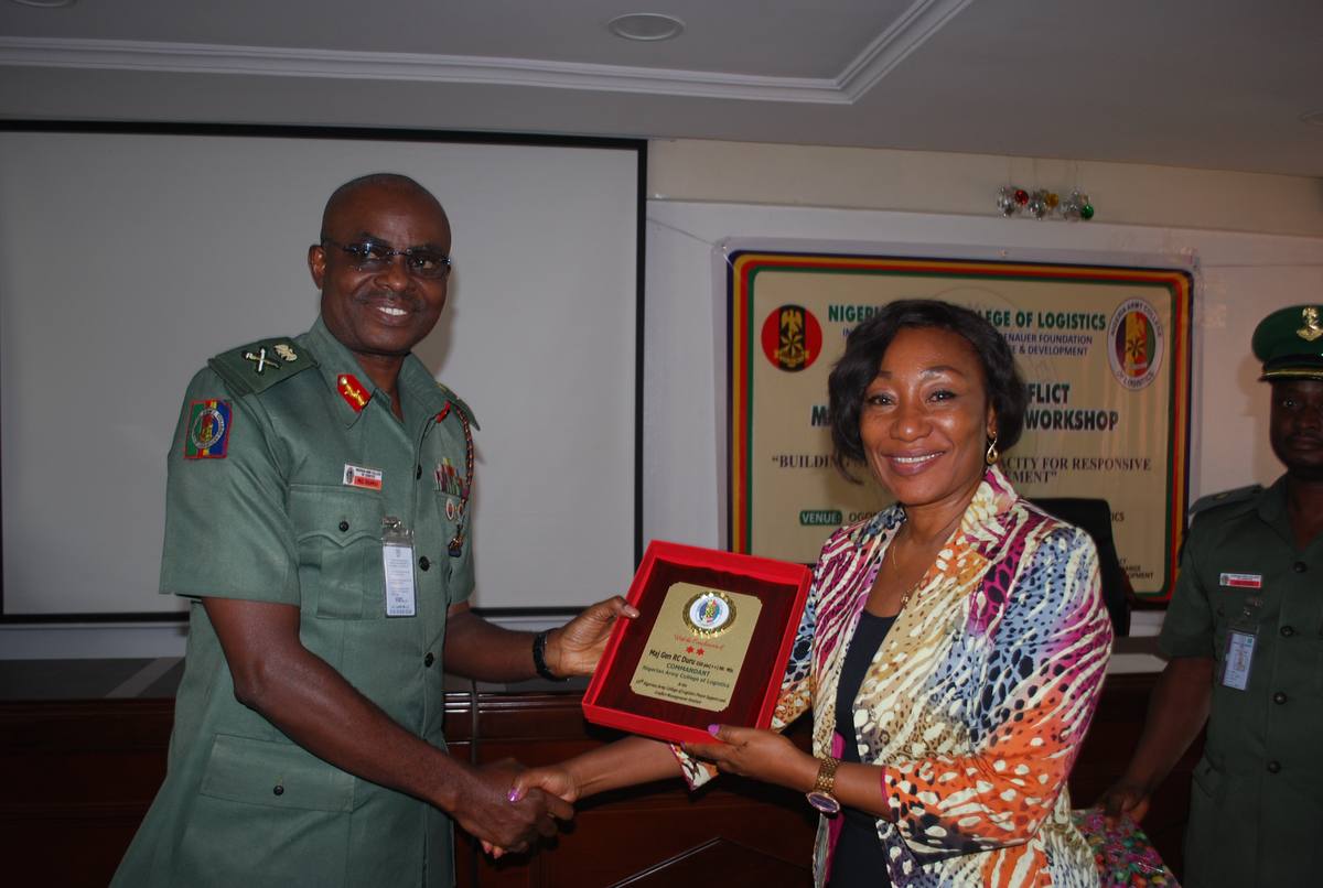 A senior officer presenting a plaque to an IMPACT trainer at the Nigerian Army College of Logistics.