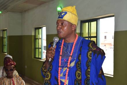 A traditional ruler speaking into a microphone at the forum.